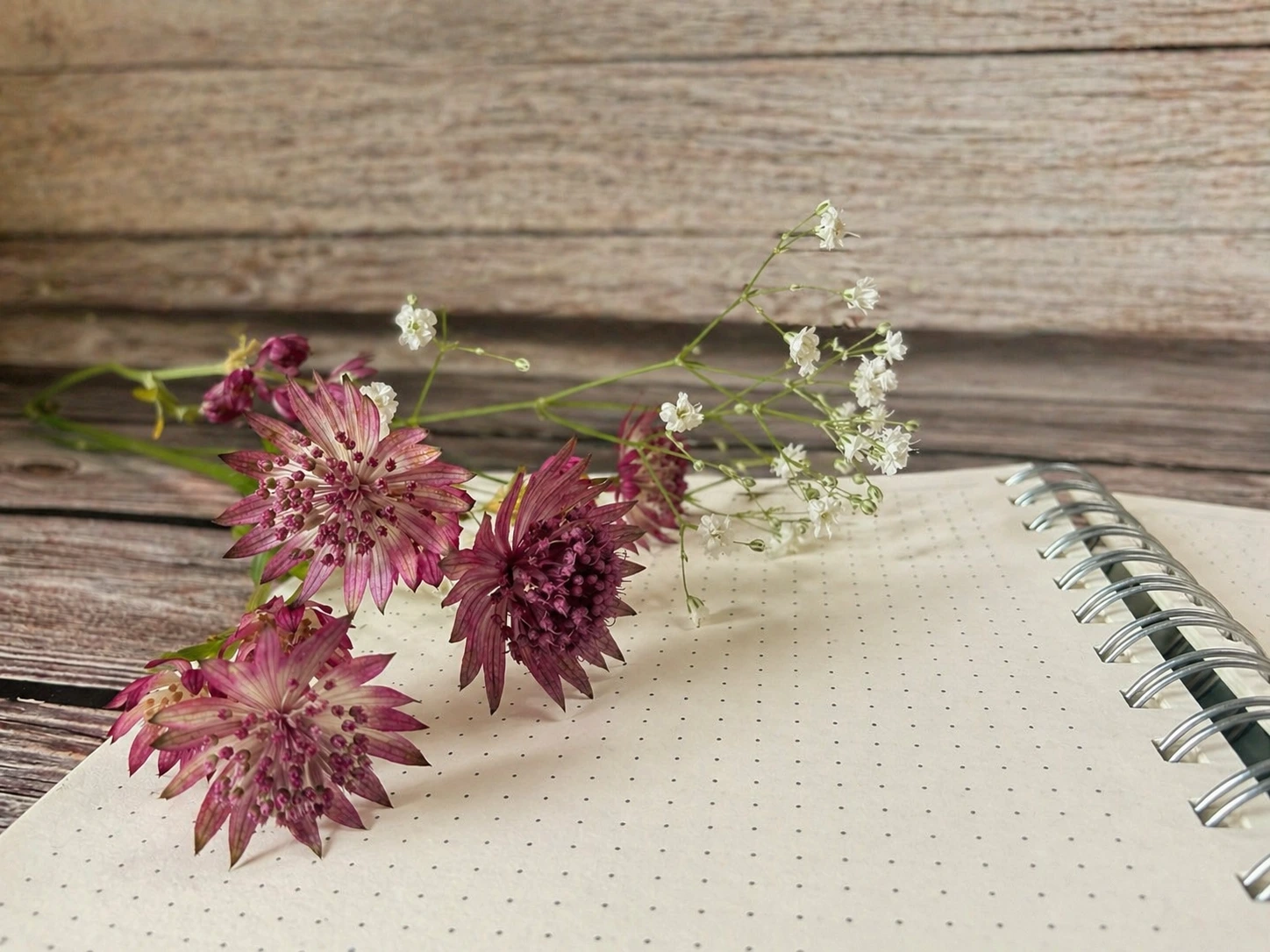 Leeres Notizbuch mit gepunkteten Seiten und Blumen auf einem Holztisch &ndash; Journaling am Abend vorbereiten