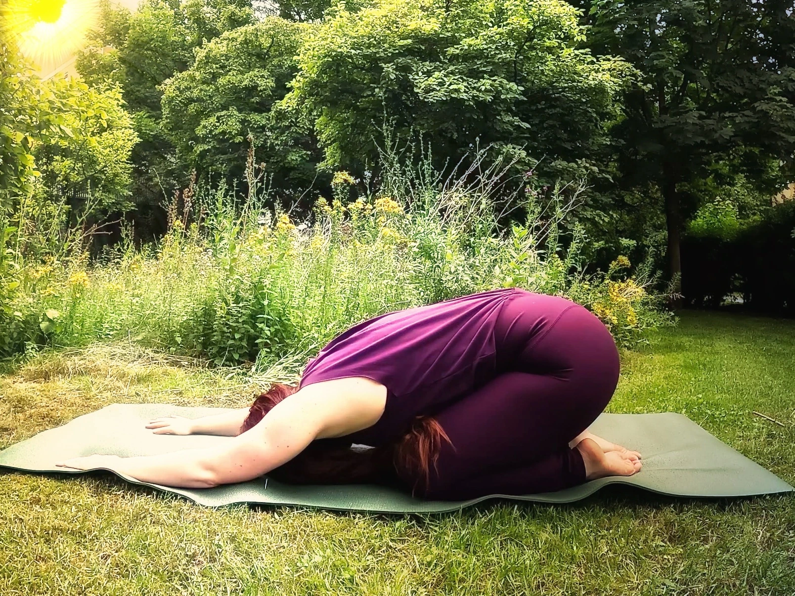 Kindhaltung (Balasana) auf einer Yogamatte im Garten während einer ruhigen Yin-Yoga-Einheit am Morgen.