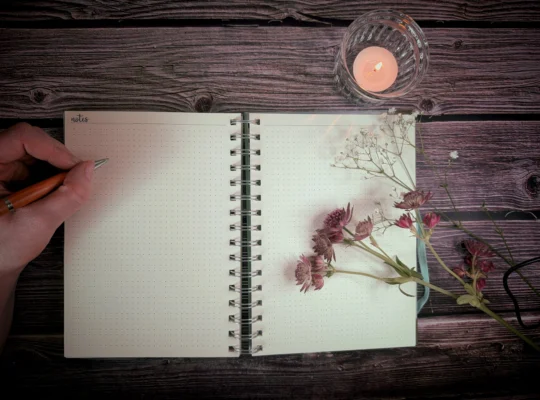 Journaling am Abend mit offenem Journal, Stift, Blumen und Kerze